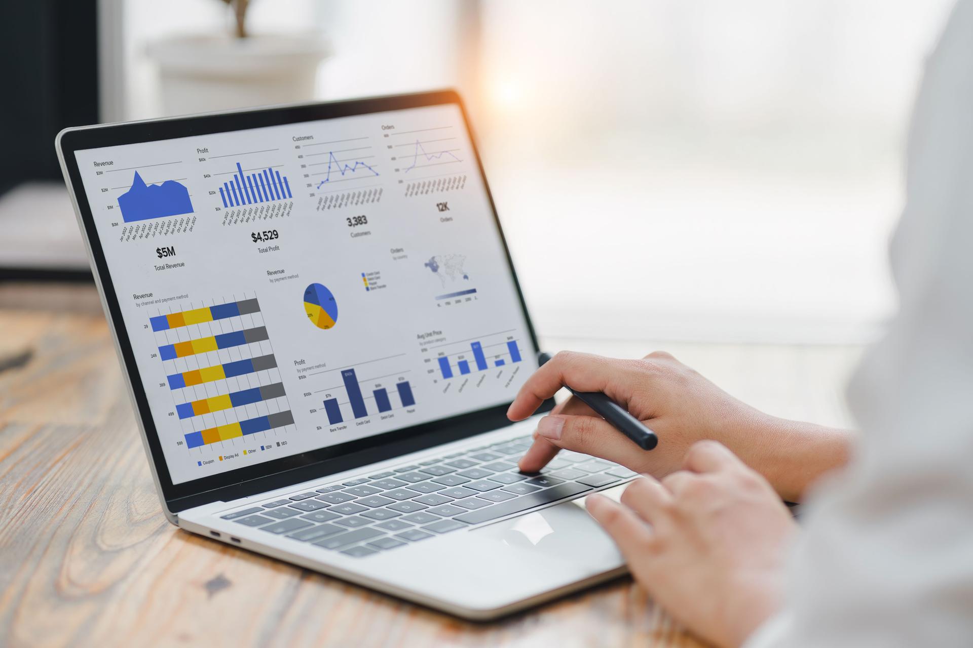 Professional analyzing financial data graphs, charts on laptop display at a modern workspace. Financial analysis or business evaluation concept